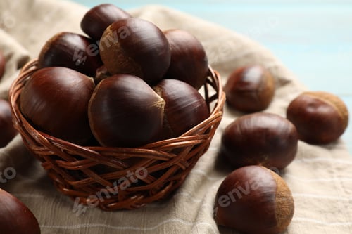 Preview: Wicker bowl with roasted edible sweet chestnuts on table, closeup
