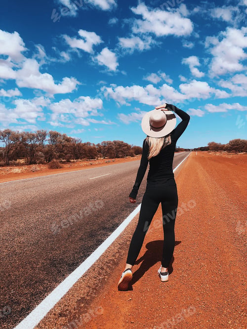 Preview: Traveler girl in a hat standing near road
