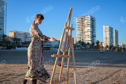 Preview: Woman Standing Next to Easel on Beach