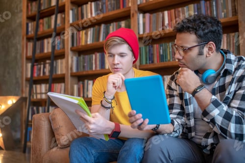 Preview: Two young men sitting on the sofa and getting ready for exams