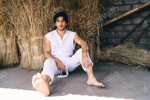 Preview: Young man resting on floor in haystack room