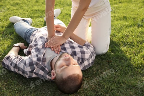 Preview: Woman doing cardiac massage to unconscious man with heart attack on green lawn