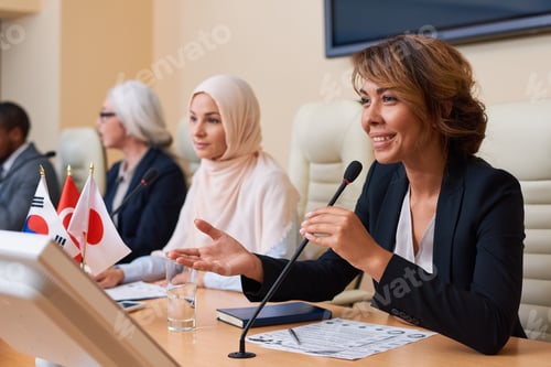 Preview: Happy young female delegate in formalwear looking at audience