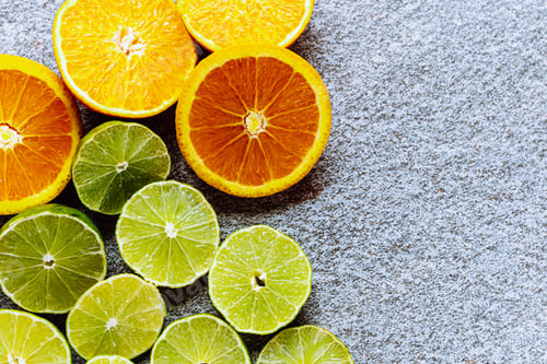 Preview: Various citrus and juicy lime and orange slices on gray stone background from above. Place to insert