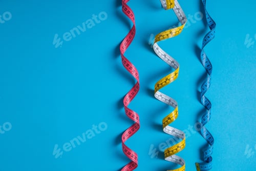 Preview: flat lay with arranged colorful measuring tapes placed in row isolated on blue