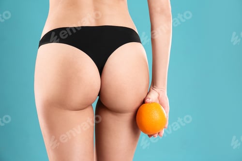 Preview: Closeup view of slim woman in underwear with orange on color background. Cellulite problem concept