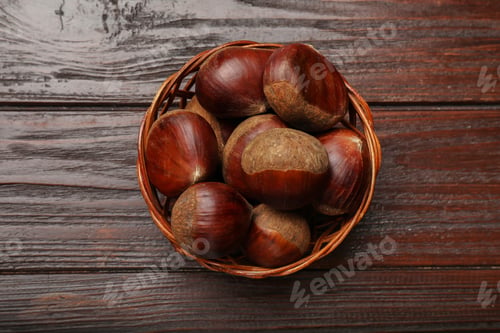 Preview: Sweet fresh edible chestnuts in wicker bowl on wooden table, top view