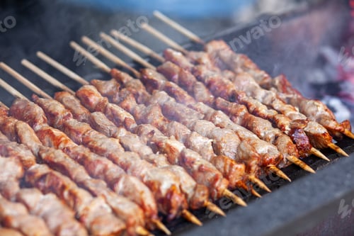 Preview: A lot of juicy meat kebabs in a row on the grill.