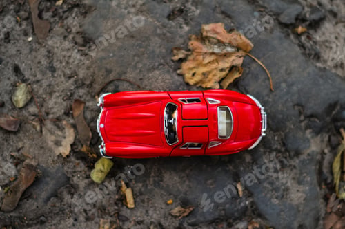 Preview: Autumn background. Red retro car on road from above. Red car moving on autumn road in dark forest