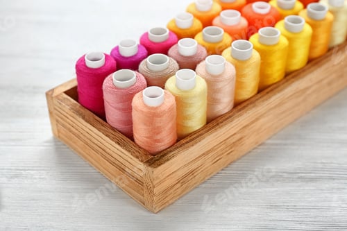 Preview: Container with set of color sewing threads on wooden background