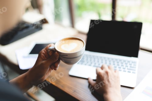 Preview: Young business man and entrepreneur drinking drinking coffee and working on laptop in office