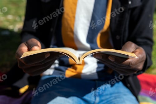 Preview: Anonymous black man reading book in park