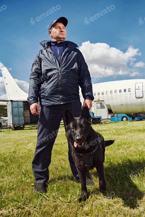 Preview: Security officer with detection dog standing outdoors at aerodrome