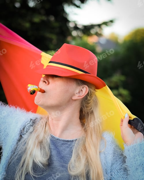 Preview: Caucasian woman holding a Belgian flag and blowing a whistle celebrating independence day