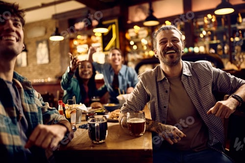 Preview: Group of happy friends watching sports match on TV in a pub.