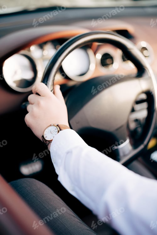 Preview: The man in white shirt sits behind the wheel of an open car, close-up