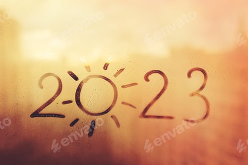 Preview: numbers 2023 of new year with shape of sun paint on splashed foggy glass on orange sunset window