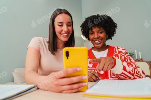 Preview: Two engaged women joyfully sharing a moment while using a bright yellow smartphone