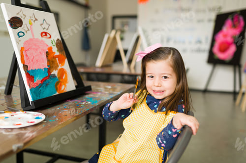Preview: Portrait of a pretty elementary girl showing her new artwork