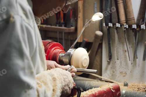 Preview: Joinery worker shaping a piece of wood on the lathe with dust from the wood everywhere