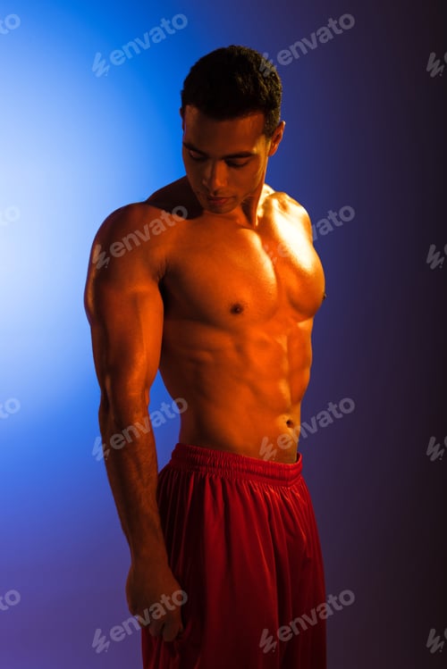 Preview: handsome sportive mixed race man with muscular torso posing at camera on blue and dark purple