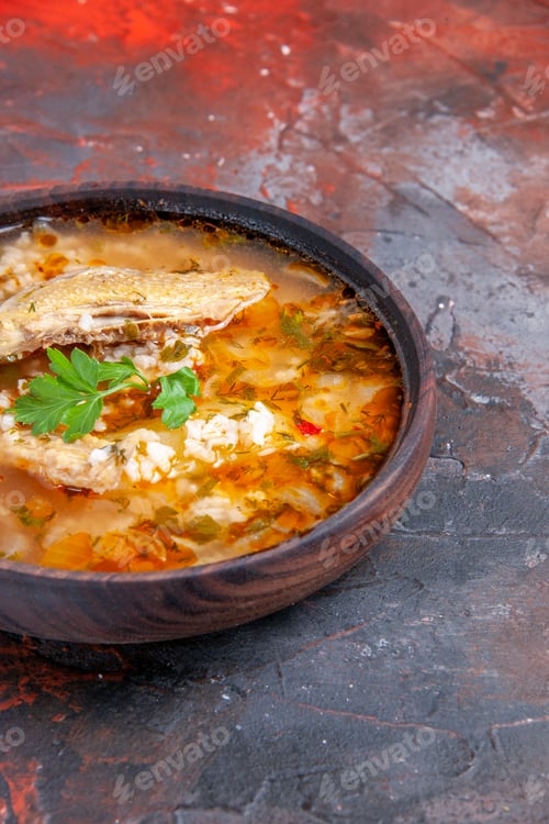 Preview: bottom view homemade chicken and rice soup in wooden bowl on dark red background