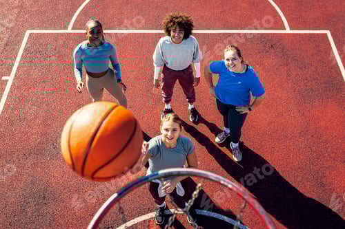 Preview: Portait of diverse group of young woman having fun playing basketball outdoors.