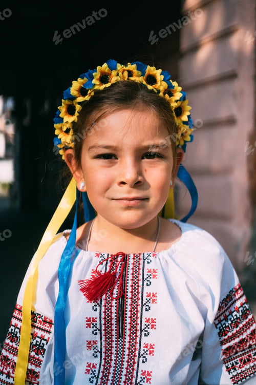 Preview: Child girl in Ukrainian traditional clothes and flower wreath is praying outdoors in a sunlight