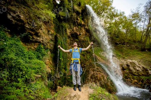 Preview: Young hiker stopped beside a mountain waterfall to rest