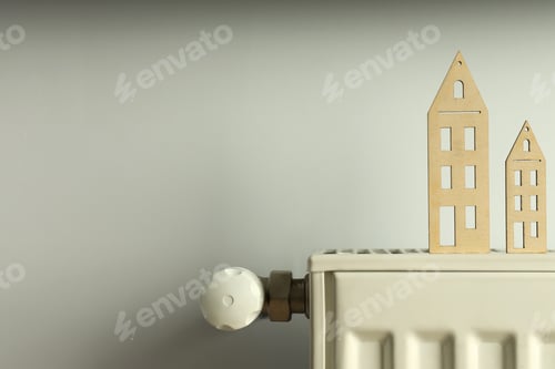 Preview: Concept of heating season with wooden houses on radiator