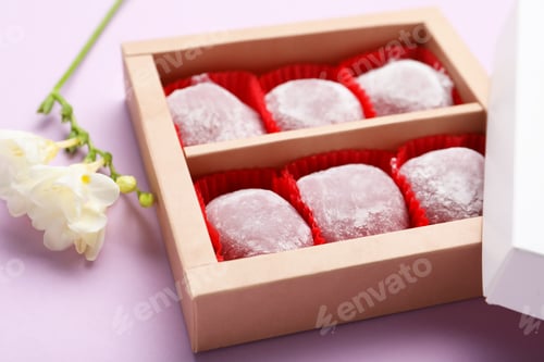 Preview: Box of delicious mochi and flowers on light background, closeup. Traditional Japanese dessert
