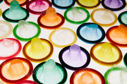 Preview: A large group of multi-colored condoms displayed on a white background. Laid out neatly.