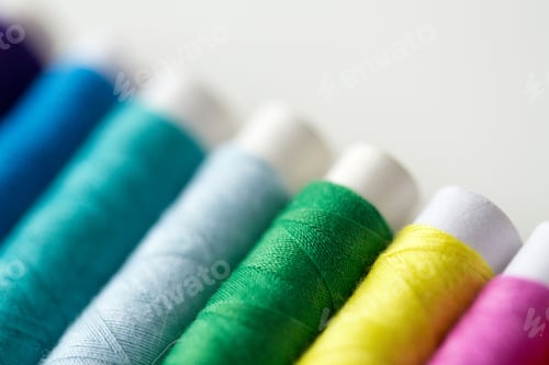 Preview: row of colorful thread spools on table