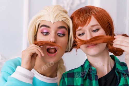 Preview: Two cheerful girlfriends play with hair and grimace.