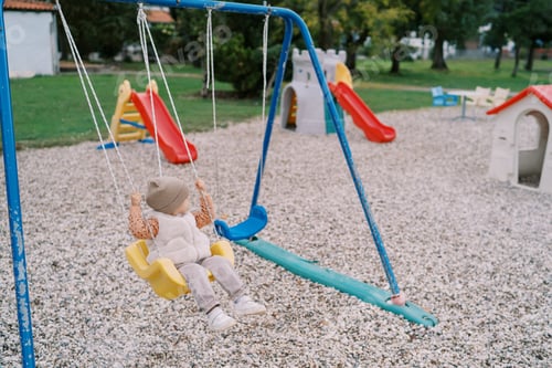 Preview: Little girl swings on a rope swing at the playground and looks away