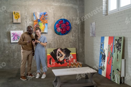 Preview: Young intercultural couple looking through their photos in smartphone