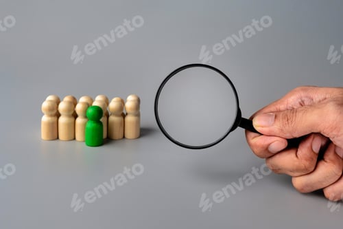 Preview: A magnifying glass is held over a row of wooden figures.