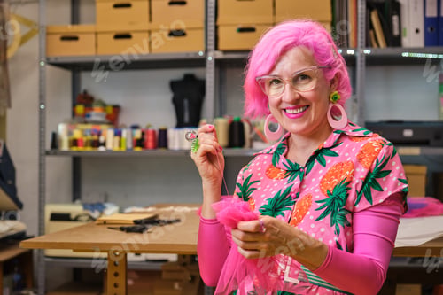 Preview: Seamstress with pink hair and colorfull clothes hand sewing a piece of fabric.