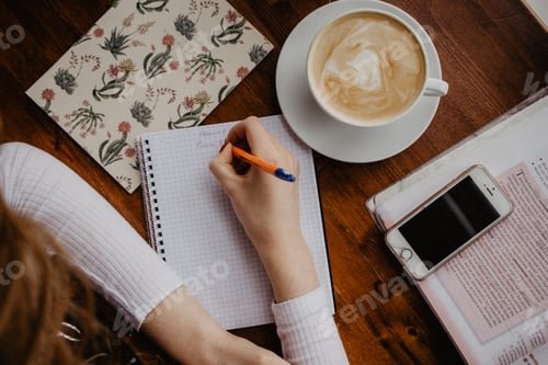 Preview: Student doing homework with a cup of cappuccino. Overhead shot