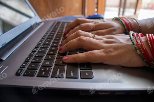 Preview: Closeup shot of a female wearing bangles and working on a laptop