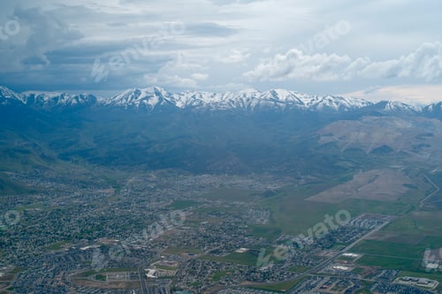 Preview: Aerial view of sprawling urban landscape with snow-capped mountains under a cloudy sky. Oregon, USA