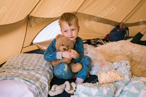 Preview: Boy hugging teddy bear in tent
