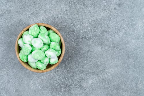 Preview: Bunch of green candies in wooden bowl