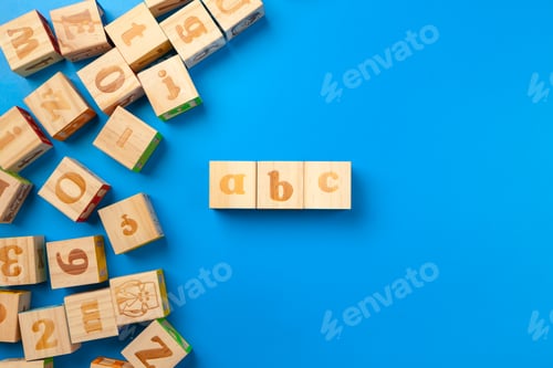 Preview: Wooden colorful alphabet blocks on blue background, flat lay, top view