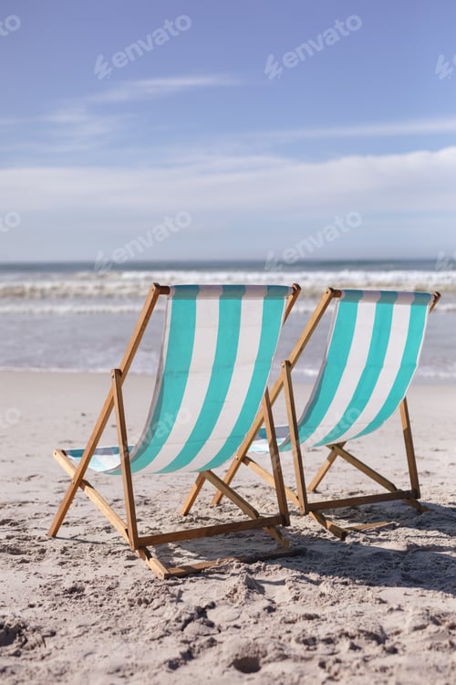 Preview: View of two deck chairs on the beach with sea waves