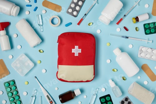 Preview: top view of red first aid kit bag on blue surface surrounded with different medicines