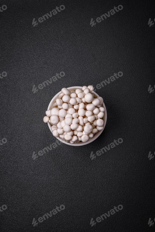 Preview: Small white edible beech mushrooms with salt and spices on a plain background