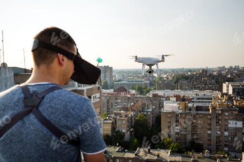 Preview: Man operating a drone with remote control on rooftop