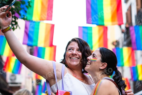 Preview: Two smiling women taking a selfie at gay pride parade