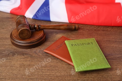 Preview: Passports in color covers, gavel and flag of United Kingdom on wooden table, closeup